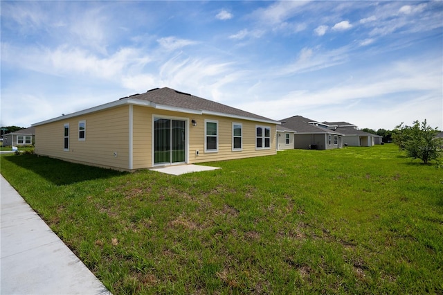 rear view of house featuring a yard and a patio