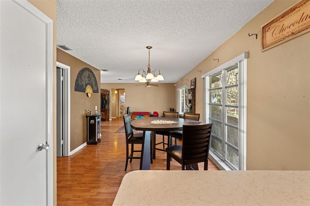 dining area featuring hardwood / wood-style floors, a notable chandelier, and a textured ceiling