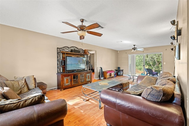 living room with ceiling fan, light hardwood / wood-style flooring, and a textured ceiling