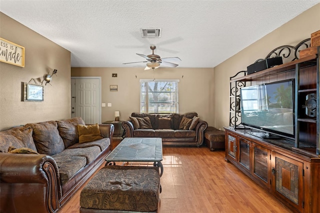 living room with ceiling fan, light hardwood / wood-style flooring, and a textured ceiling