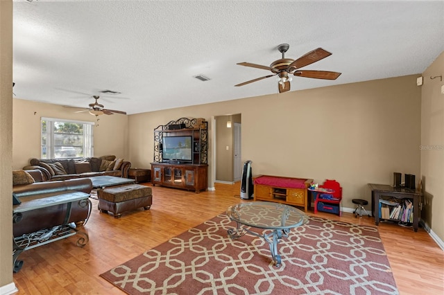 living room featuring hardwood / wood-style floors, ceiling fan, and a textured ceiling