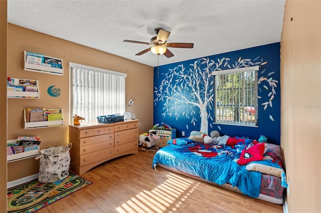 bedroom featuring ceiling fan, wood-type flooring, and a textured ceiling