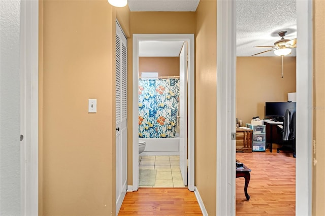 corridor featuring wood-type flooring and a textured ceiling