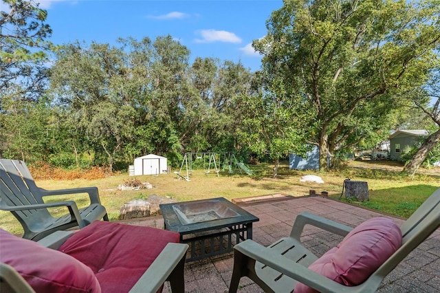 view of patio / terrace featuring a fire pit, a storage unit, and a playground