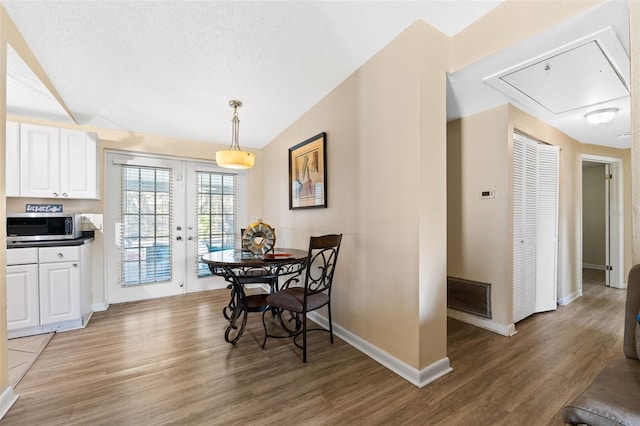 dining room with french doors, a textured ceiling, hardwood / wood-style flooring, and lofted ceiling