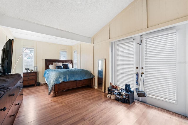 bedroom with hardwood / wood-style flooring, a textured ceiling, and vaulted ceiling