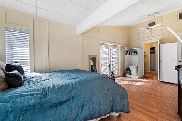 bedroom with hardwood / wood-style flooring, ceiling fan, vaulted ceiling with beams, and multiple windows