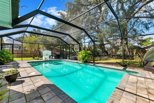 view of swimming pool featuring glass enclosure and a patio