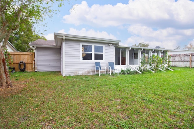 rear view of property featuring a yard and a sunroom