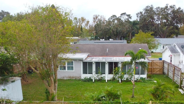 back of property with a sunroom and a lawn