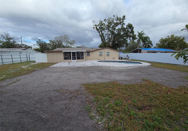 back of property featuring a fenced in pool, a patio area, and a sunroom