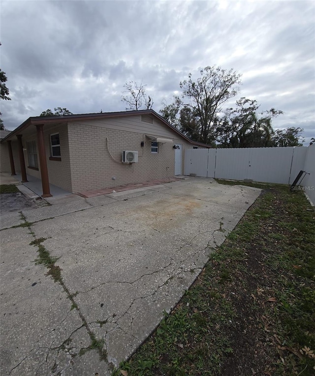 view of home's exterior with a wall unit AC and a patio