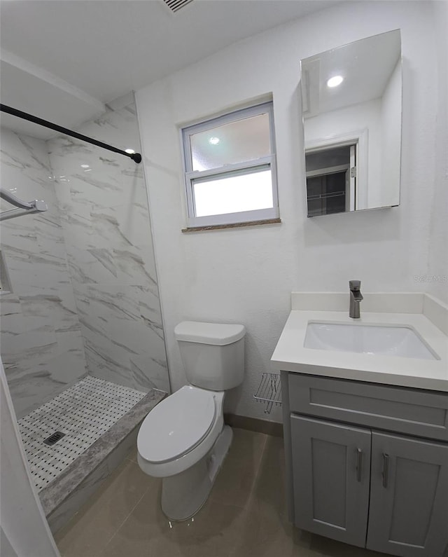 bathroom featuring a tile shower, vanity, and toilet