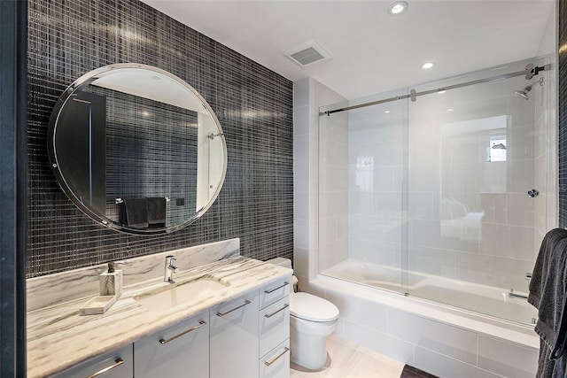 full bathroom featuring vanity, shower / bath combination with glass door, tile patterned flooring, toilet, and tile walls