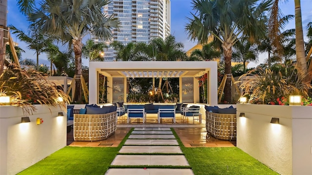 patio terrace at dusk featuring outdoor lounge area and a pergola