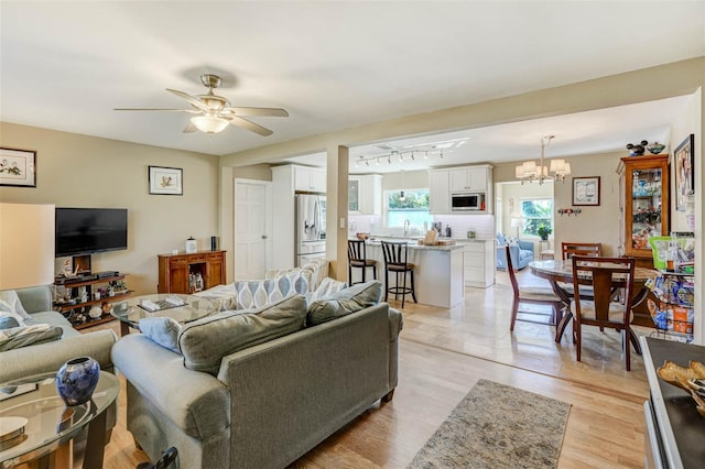 living room with light hardwood / wood-style flooring, ceiling fan with notable chandelier, and sink