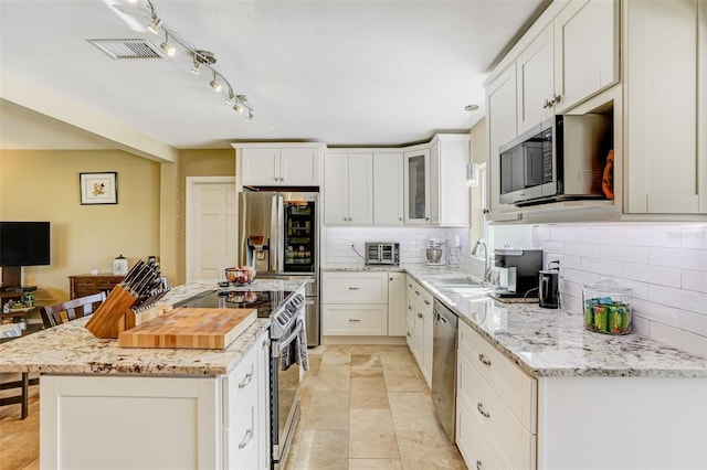 kitchen with white cabinets, sink, decorative backsplash, light stone counters, and stainless steel appliances