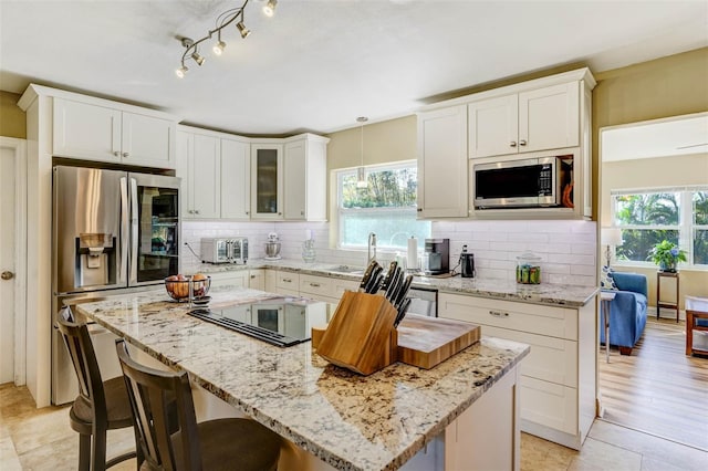 kitchen with a center island, stainless steel appliances, white cabinetry, and a healthy amount of sunlight