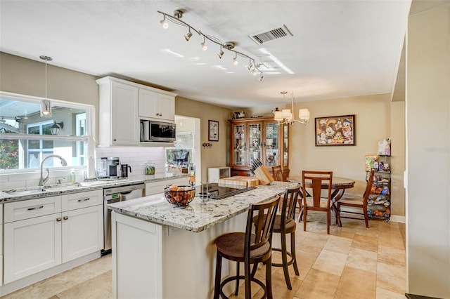 kitchen with tasteful backsplash, white cabinetry, a kitchen island, and appliances with stainless steel finishes