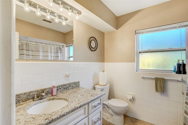 bathroom with vanity, tile patterned floors, a shower with shower curtain, toilet, and tile walls