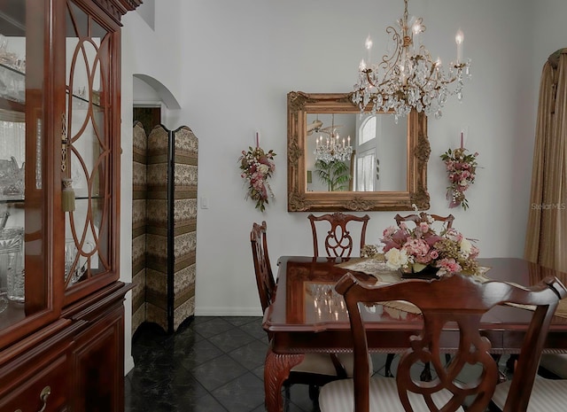 dining space with dark tile patterned flooring and an inviting chandelier