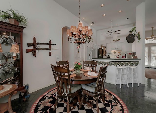 dining space with vaulted ceiling, dark tile patterned flooring, and ceiling fan with notable chandelier