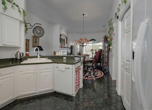 kitchen with white appliances, sink, pendant lighting, an inviting chandelier, and white cabinets