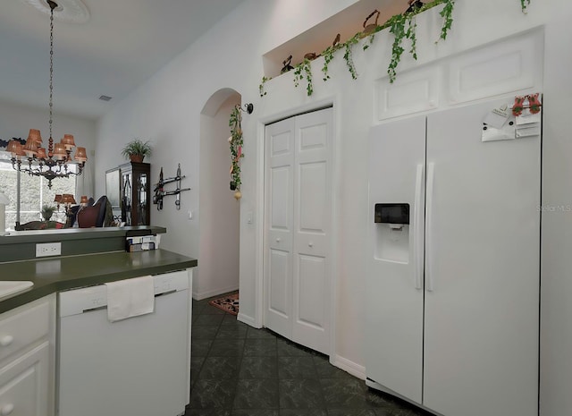 kitchen featuring a chandelier, white appliances, white cabinets, and hanging light fixtures