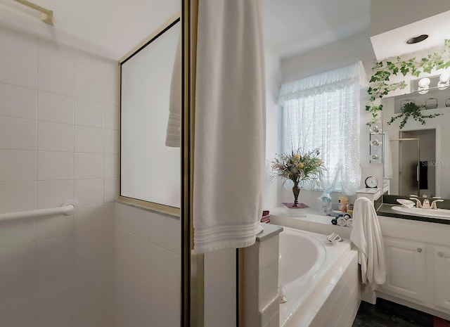 bathroom featuring tiled tub and vanity