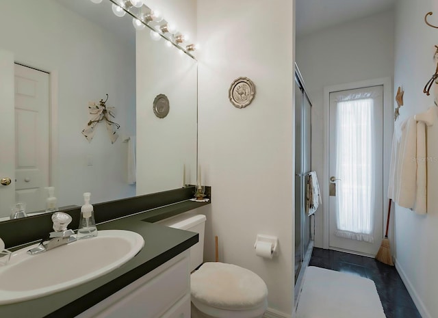 bathroom with vanity, a healthy amount of sunlight, an enclosed shower, and toilet