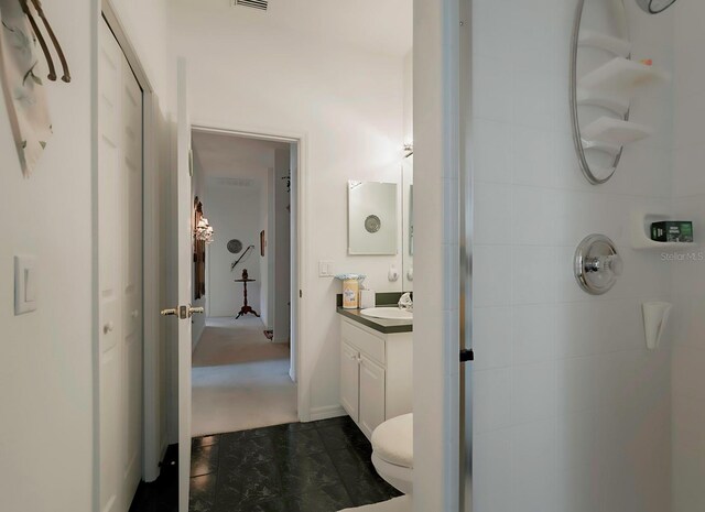 bathroom with a tile shower, vanity, toilet, and tile patterned floors