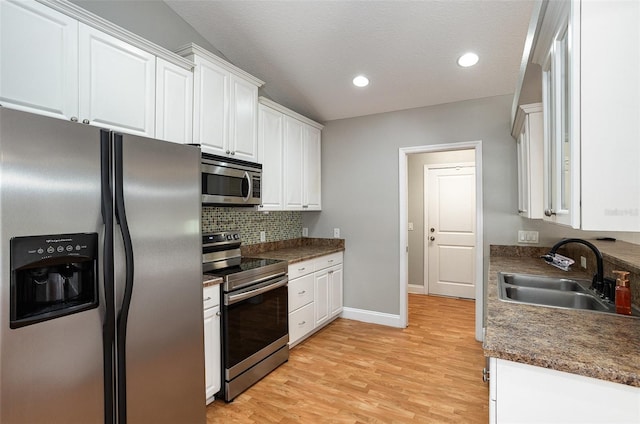 kitchen featuring sink, backsplash, light hardwood / wood-style floors, white cabinets, and appliances with stainless steel finishes