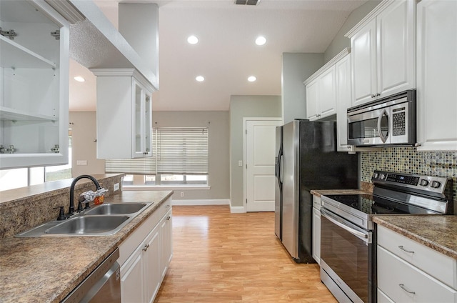 kitchen featuring appliances with stainless steel finishes, backsplash, sink, light hardwood / wood-style flooring, and white cabinets