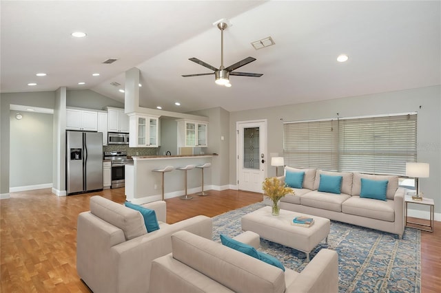 living room with light wood-type flooring, vaulted ceiling, and ceiling fan