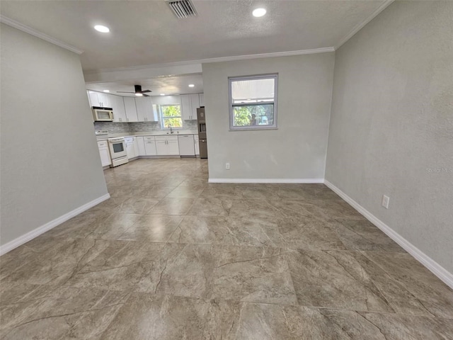 unfurnished living room with ceiling fan, ornamental molding, and sink