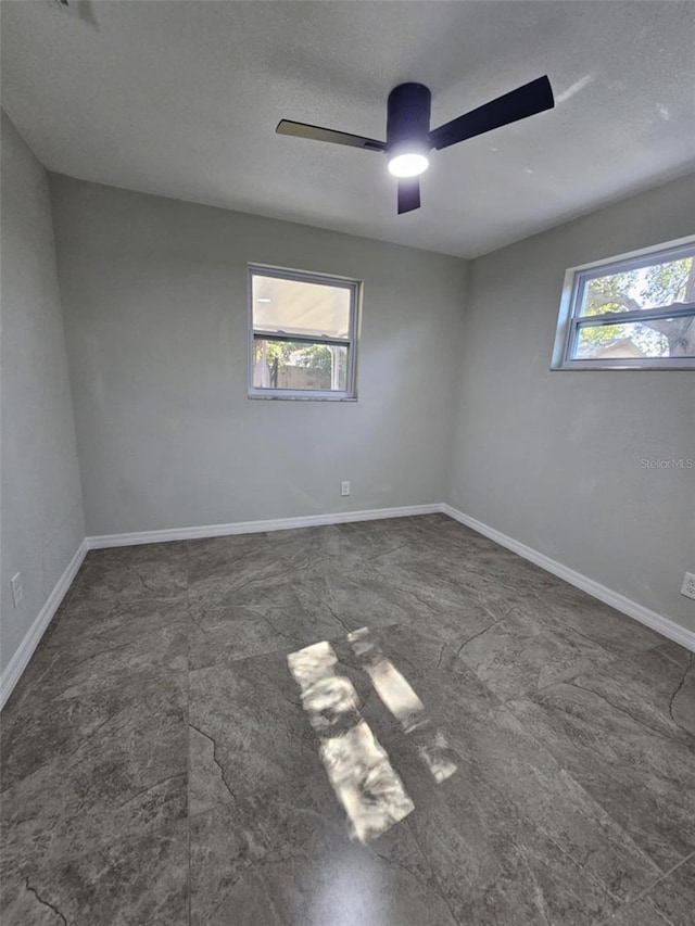 unfurnished room with ceiling fan and a textured ceiling