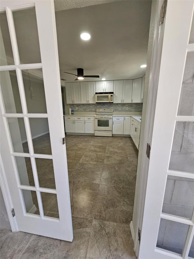 kitchen featuring white cabinets, decorative backsplash, white appliances, and ceiling fan