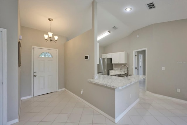 tiled entrance foyer with an inviting chandelier, vaulted ceiling, and sink