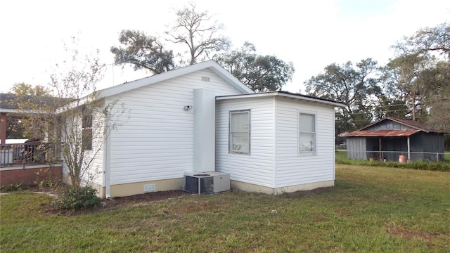 view of side of property featuring cooling unit and a yard