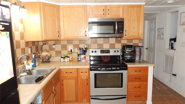 kitchen featuring decorative backsplash, stainless steel appliances, sink, light brown cabinets, and tile patterned flooring