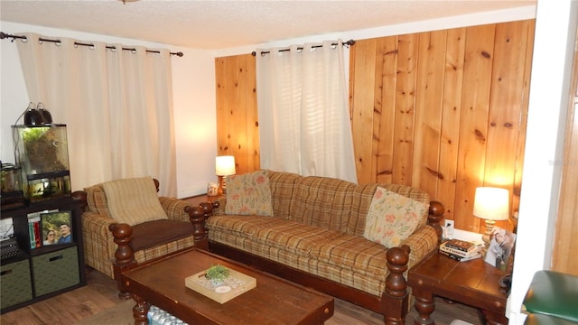 living room featuring hardwood / wood-style floors, a textured ceiling, and wood walls