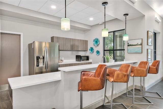 kitchen featuring a kitchen bar, appliances with stainless steel finishes, kitchen peninsula, and dark hardwood / wood-style floors