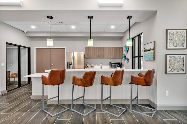 kitchen featuring dark hardwood / wood-style floors, a kitchen bar, stainless steel appliances, and hanging light fixtures