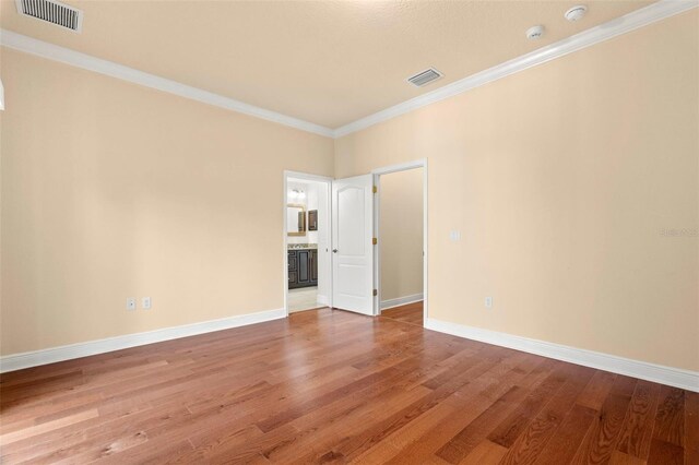 empty room with hardwood / wood-style floors and ornamental molding