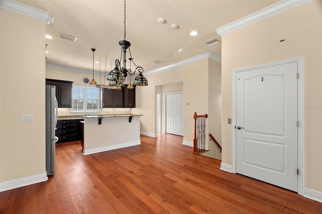 562 Rivercrest Ln, Tarpon Springs, FL 34689 - kitchen featuring crown molding, a kitchen bar, light countertops, freestanding refrigerator, and wood finished floors