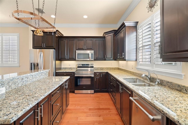 kitchen with light stone countertops, appliances with stainless steel finishes, light wood-type flooring, crown molding, and sink