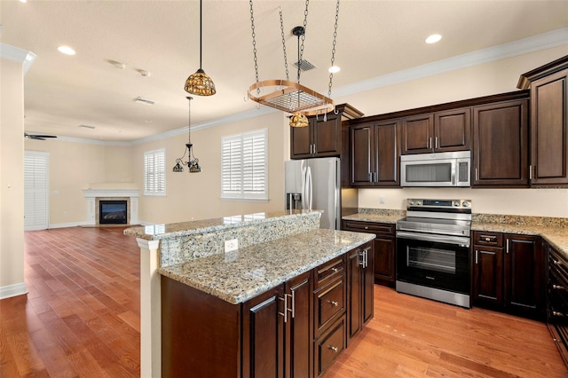 kitchen with dark brown cabinetry, pendant lighting, stainless steel appliances, and light wood-type flooring