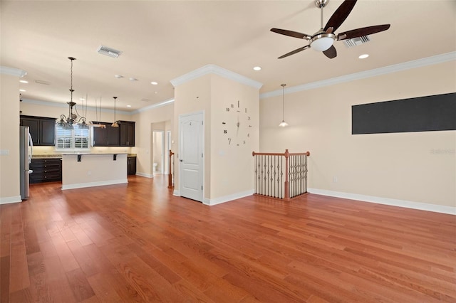 unfurnished living room with hardwood / wood-style floors, ceiling fan with notable chandelier, and crown molding