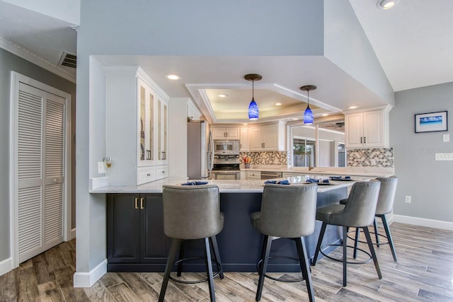 kitchen featuring white cabinets, appliances with stainless steel finishes, a breakfast bar, and kitchen peninsula