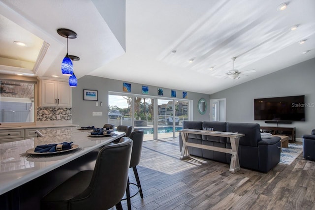 living room with vaulted ceiling, ceiling fan, and dark wood-type flooring